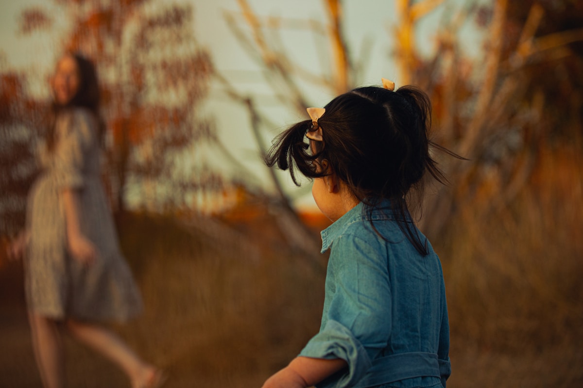 a little girl standing next to a woman in a field