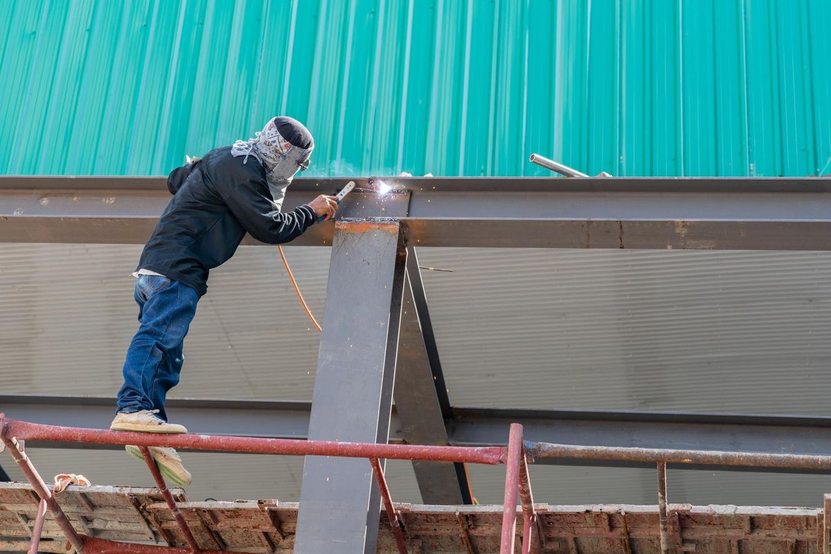 A welder is welding steel on a steel roof truss