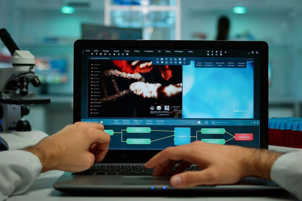 Pov shot of biochemist analysing vaccine evolution on laptop sitting at desk working, examining virus symptoms. In background lab researcher checking and preparing chemical utensils