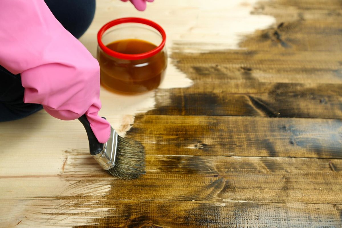 Applying protective varnish to wooden fence on bright background