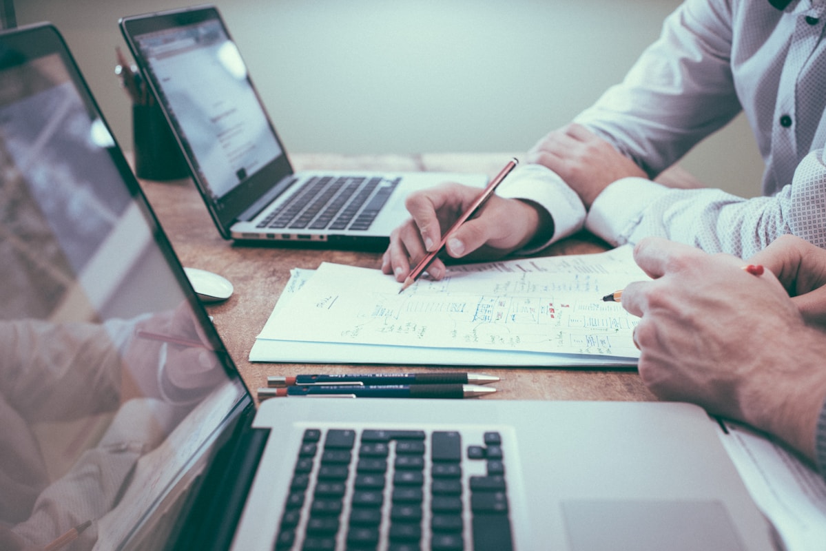 person holding pencil near laptop computer. the effort of finding new leads for insurance brokers versus the easiness of using AI for Lead Qualification in the future