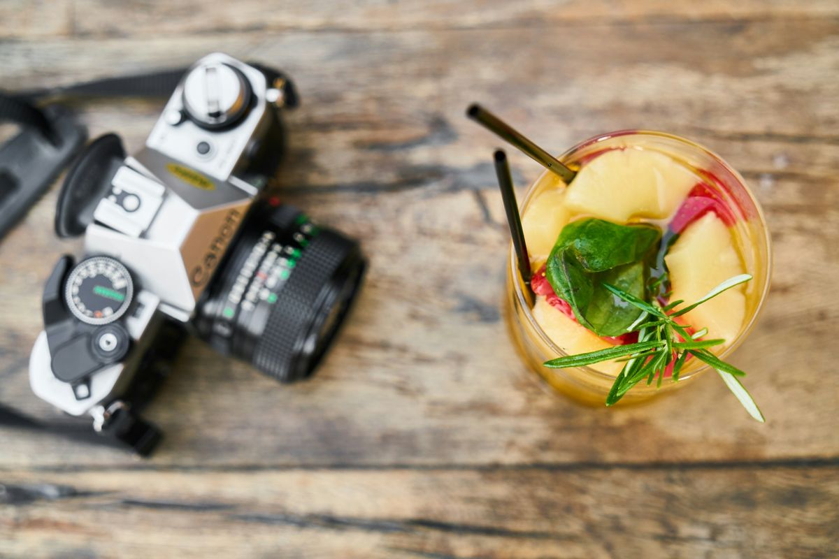 black and silver dslr camera beside green and yellow fruit in clear glass bowl