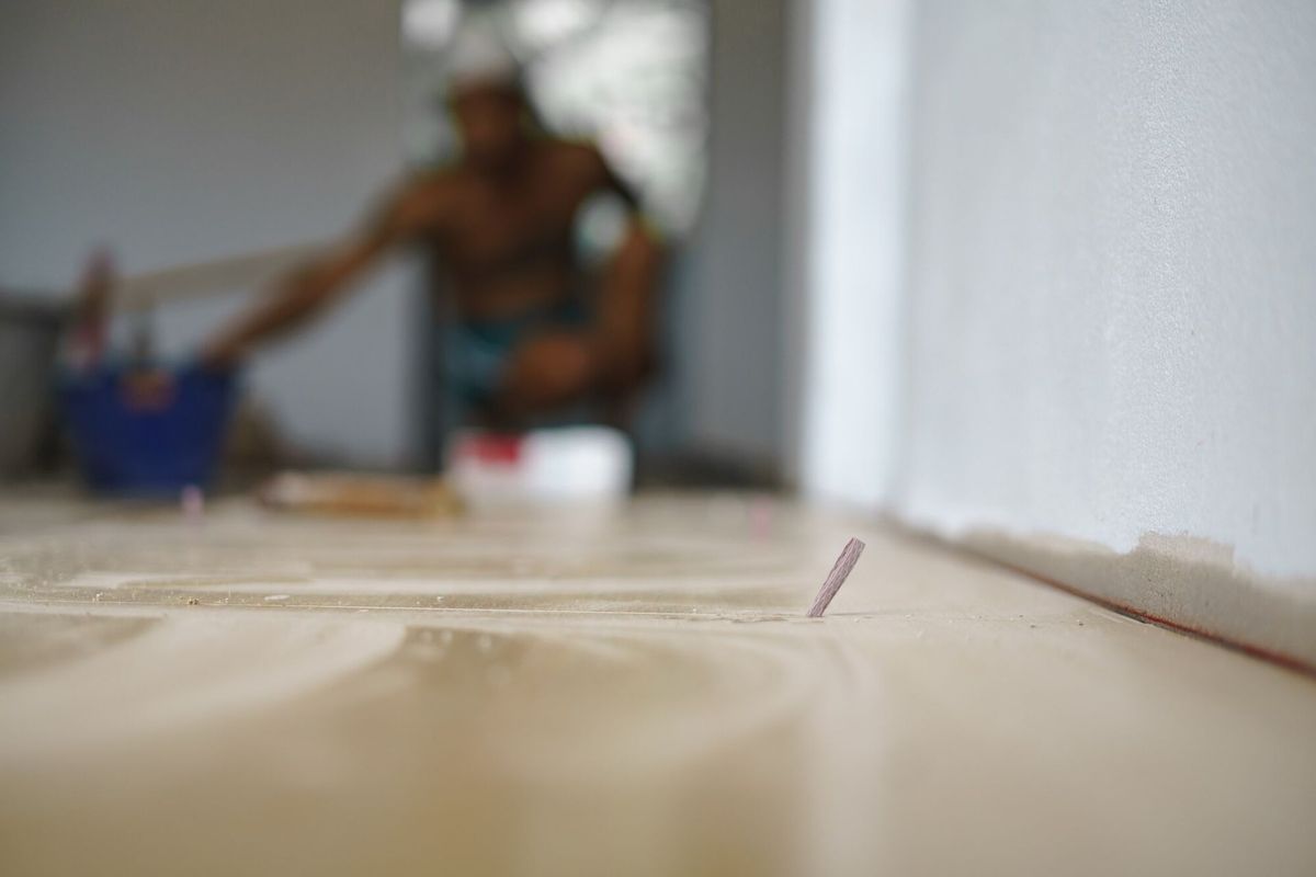 Laying ceramic floor tiles with piece of paper for leveling a gap