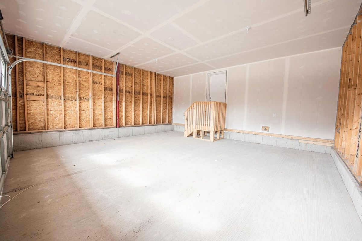 Interior of an unfinished garage parking with wooden stairs to a white door