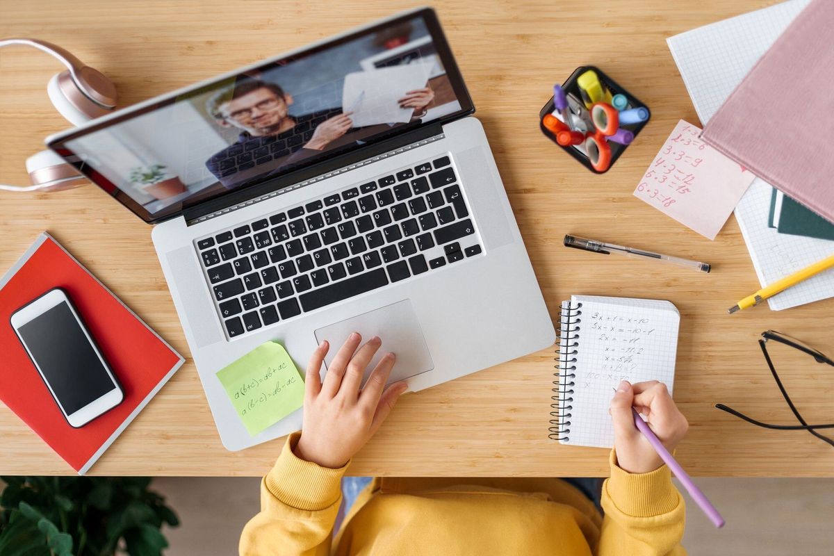 Top view of video conference with teacher on laptop at home.