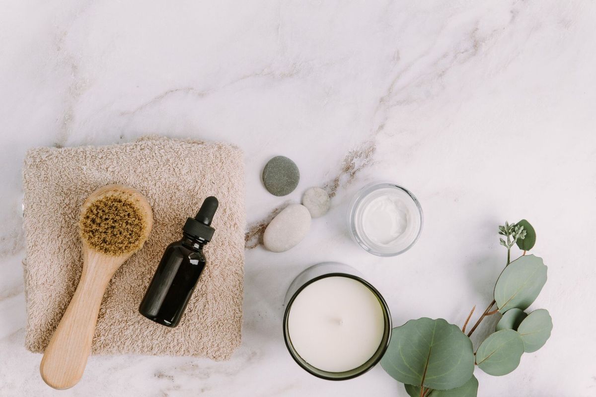 Skin care products flat lay  body or face brush and serum bottle on beige towel aroma candle