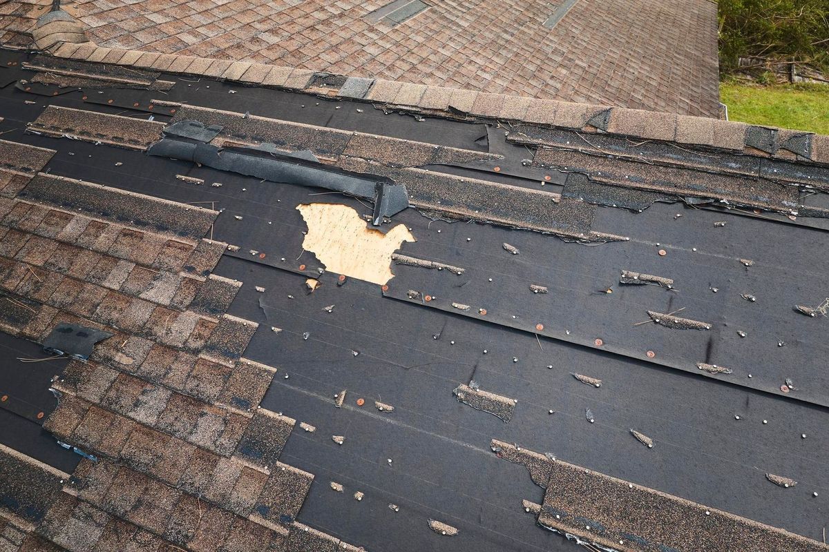 Damaged house roof with missing shingles after hurricane Ian in Florida Consequences of natural disaster