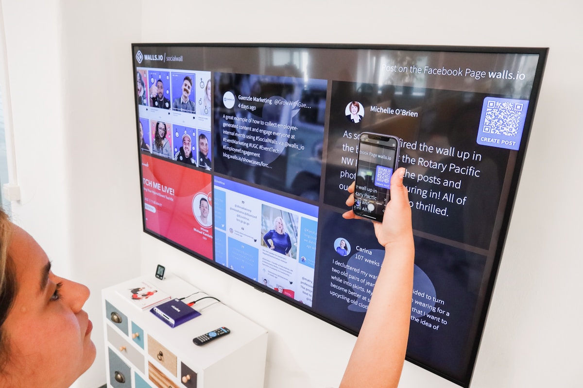 a woman holding a cell phone in front of a flat screen tv