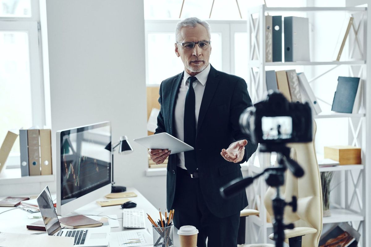 Senior man in elegant business suit sharing his business experience while making social media video