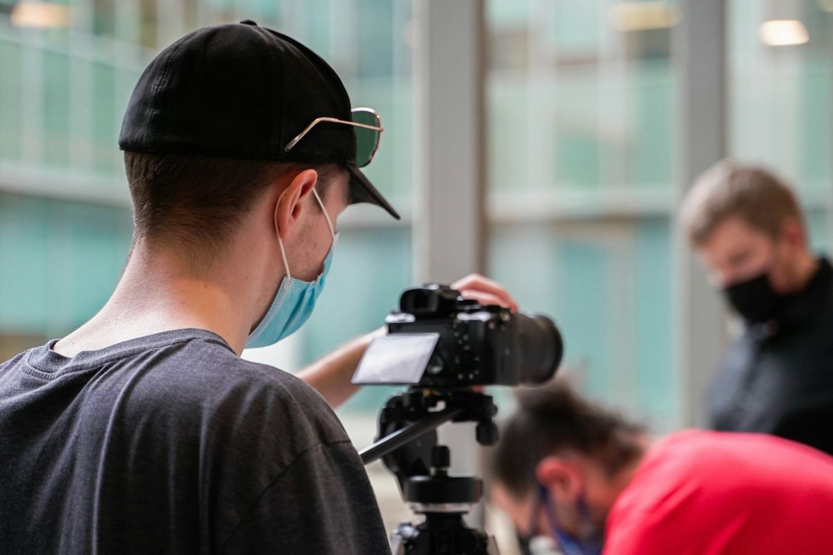 a man wearing a face mask while filming another man