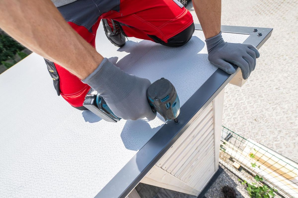 Roofer Installing Metal Trim on a Residential Building Roof on a Sunny Day