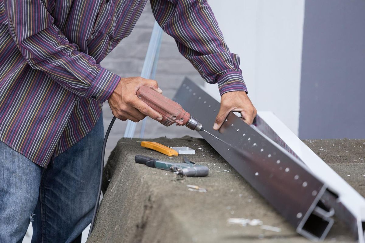 Midsection of man drilling metal