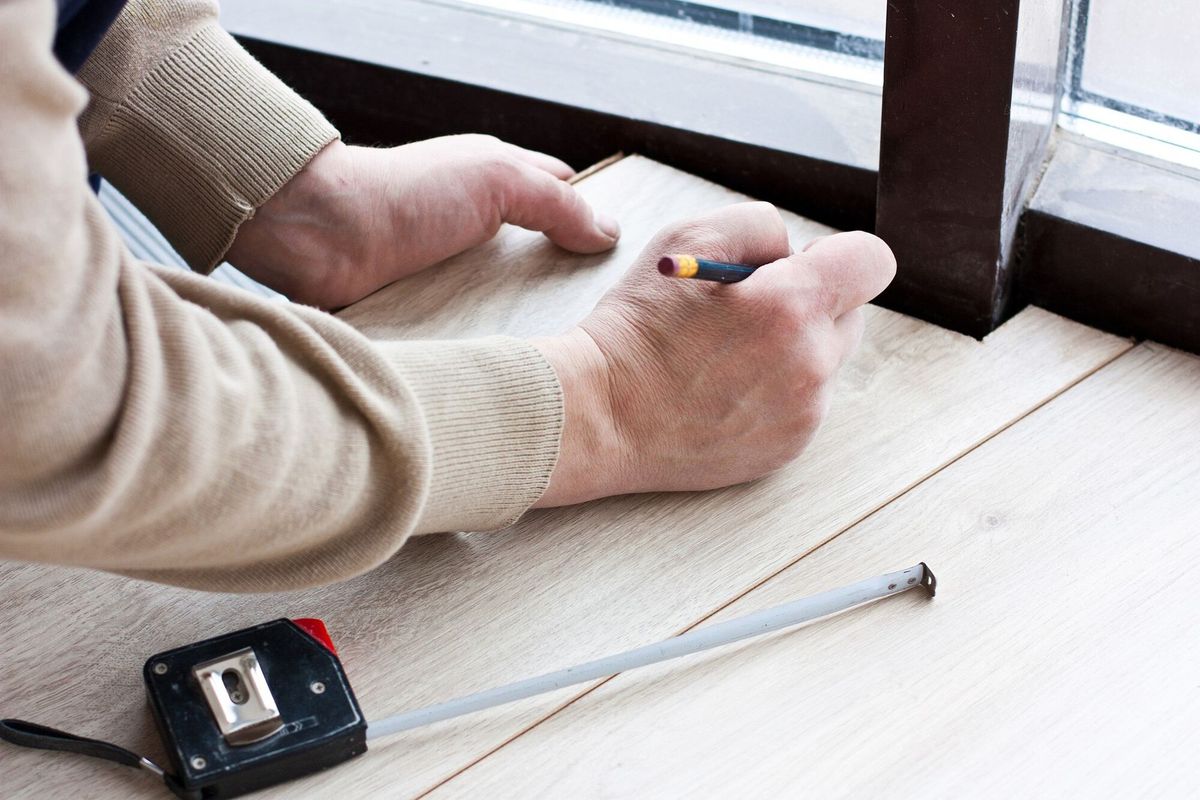 Worker makes markup for laying laminate flooring