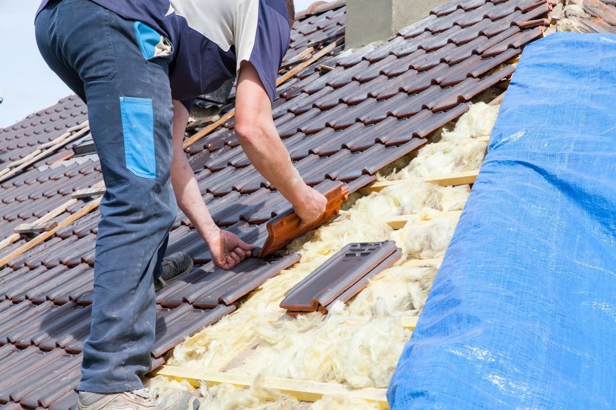 A roofer laying tile on the roof