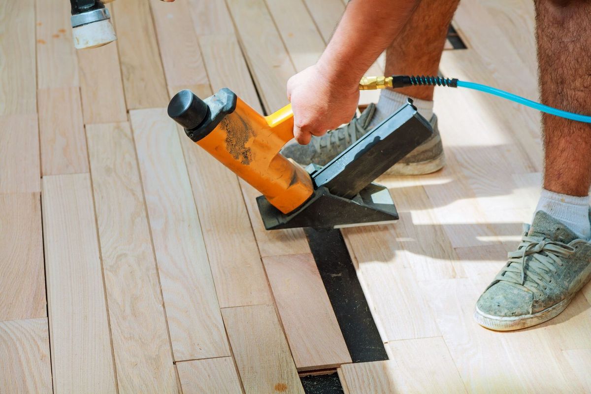 Carpenter worker installing wood parquet board