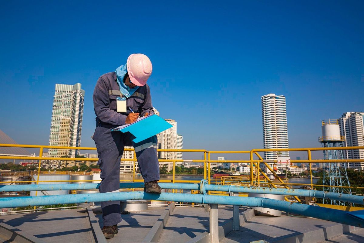 Male worker inspection visual roof storage tank oil background city and blue sky