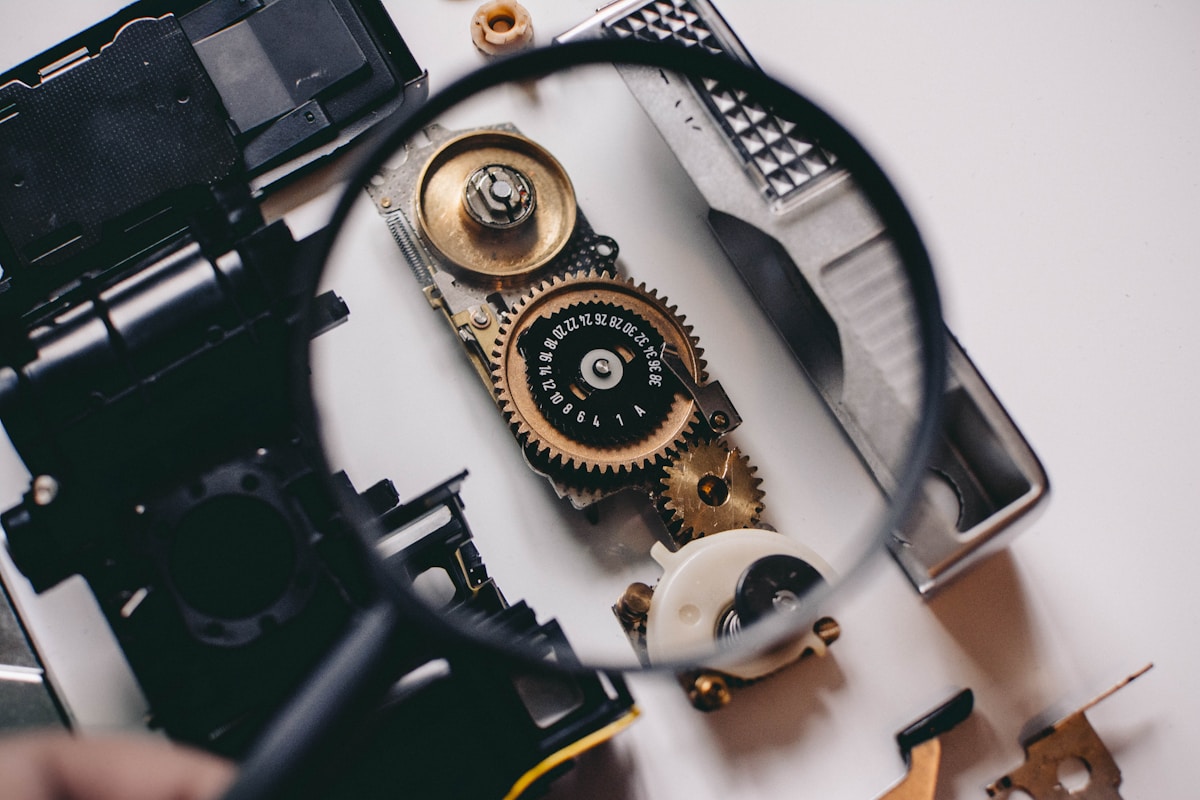 person using magnifying glass to see gold and white device gear. in this case an analogy in finding the right leads for the insurance agencies