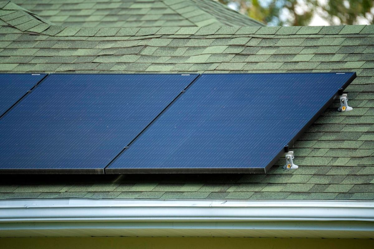 Ordinary residential house in USA with rooftop covered with solar photovoltaic panels for producing of clean ecological electrical energy in suburban rural area Concept of autonomous home