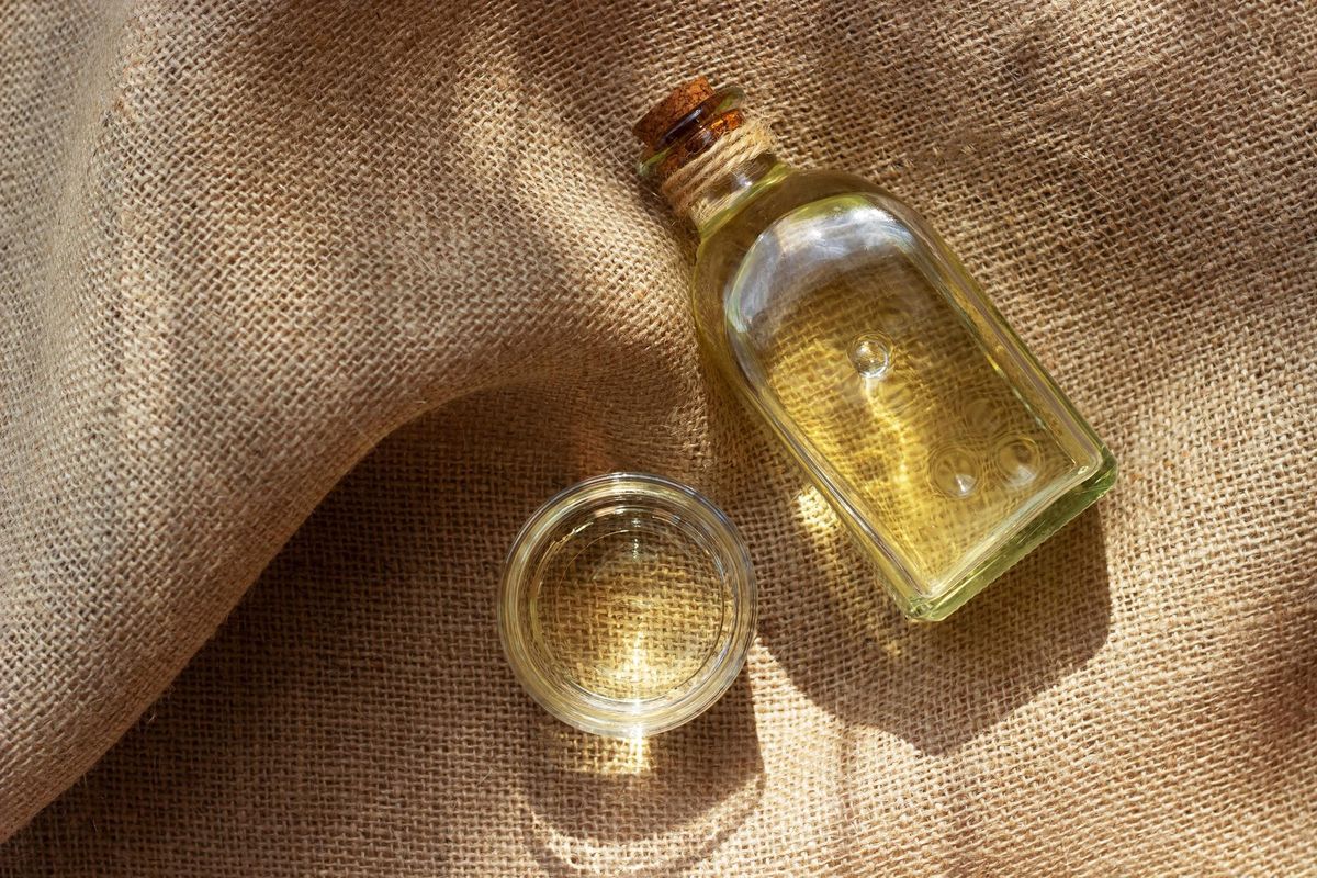 Vegetable oil in a bottle glass on burlap canvas fabric background