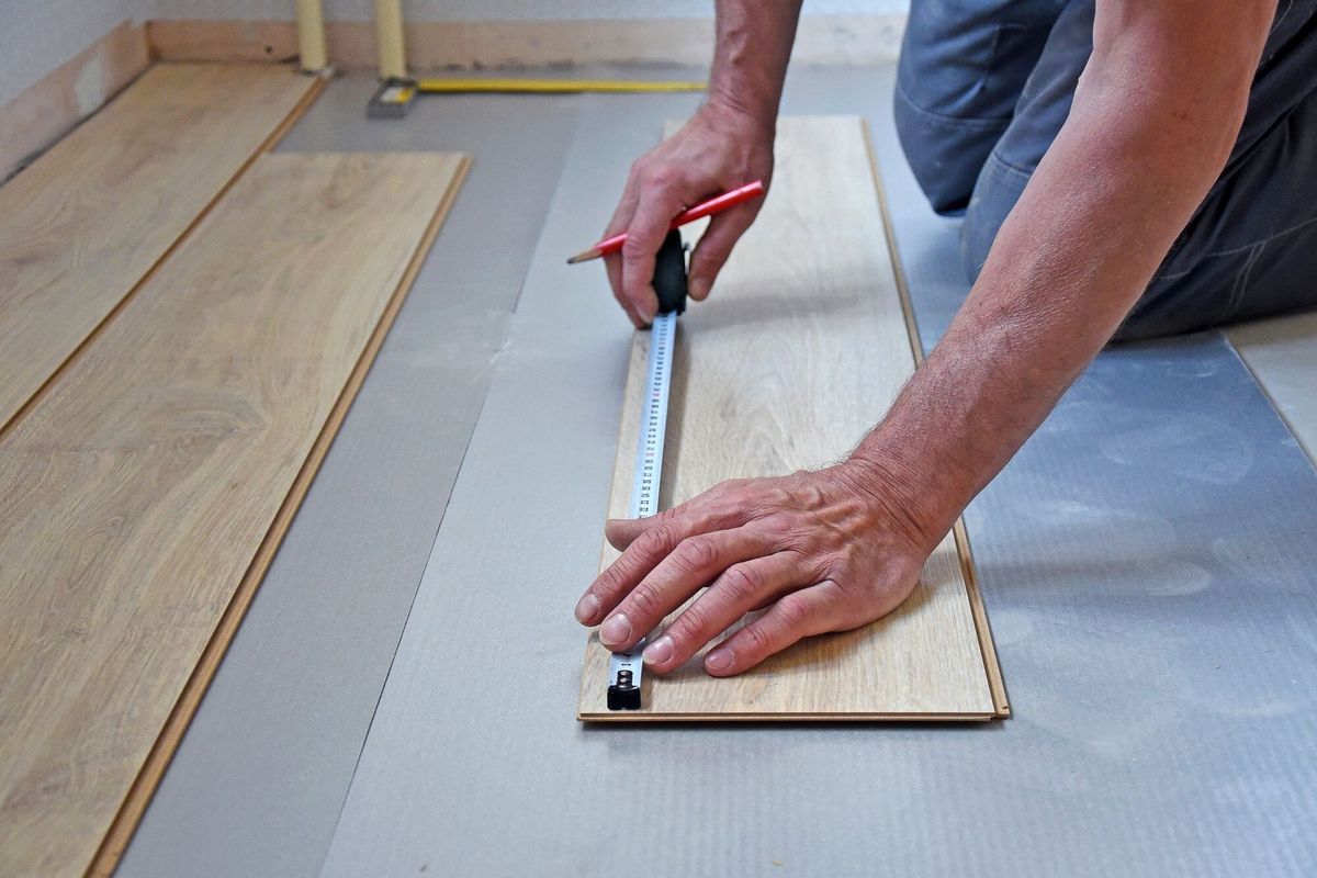 Working carpenter lays laminate flooring in the apartment. The concept of working professions.