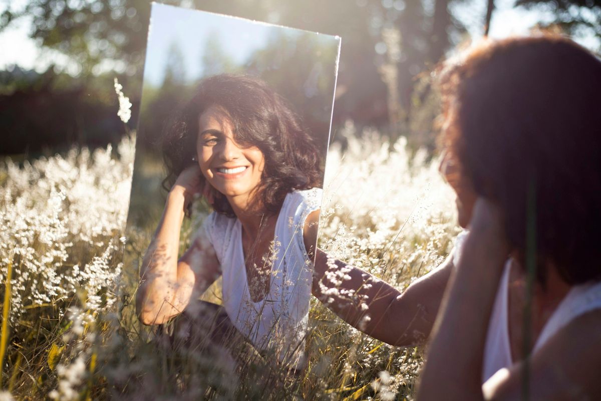 woman in blue and white floral shirt holding her face