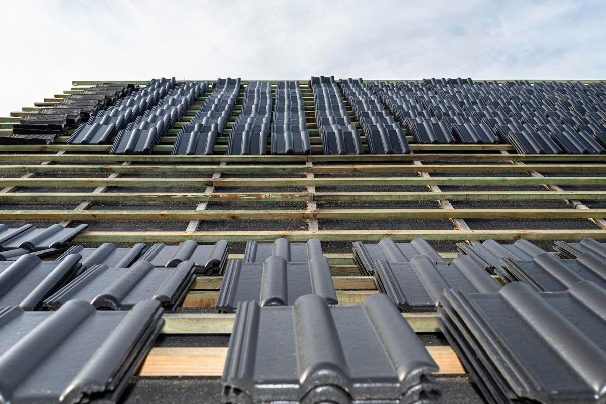 Roof ceramic tile arranged in packets on the roof on roof battens  laying tiles on a boarded roof