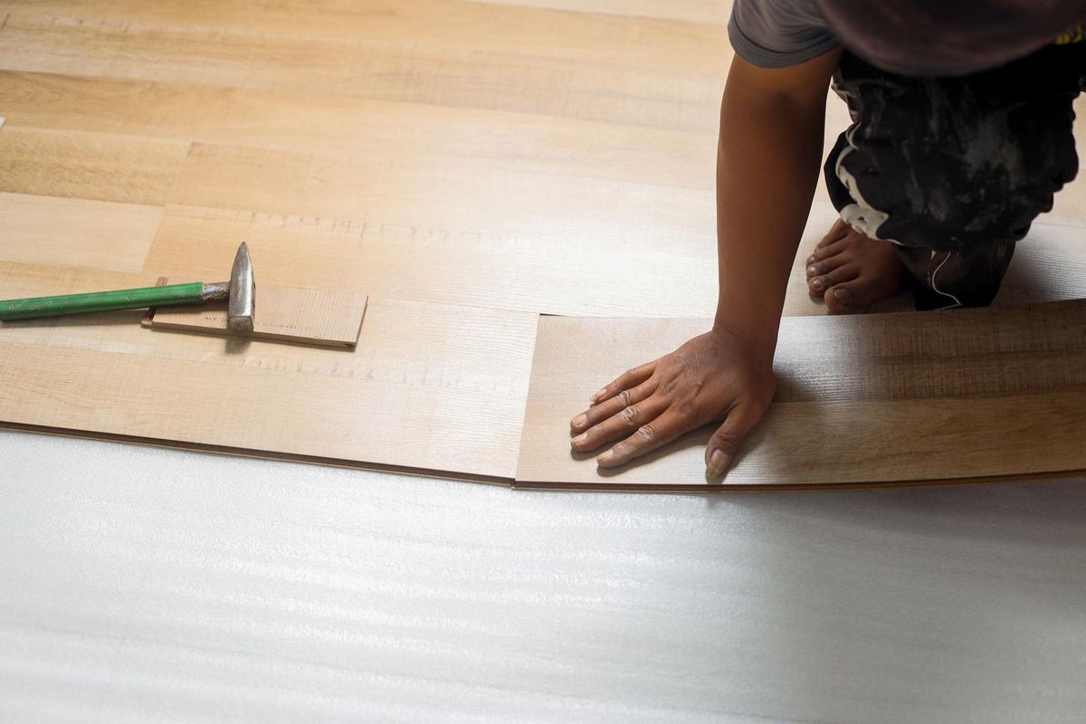 worker joining vinyl floor covering at home renovation