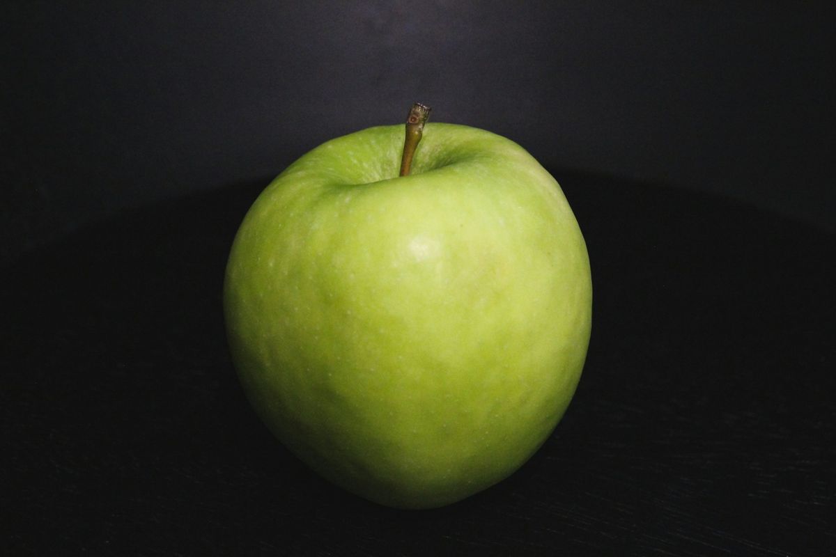 a green apple sitting on top of a table