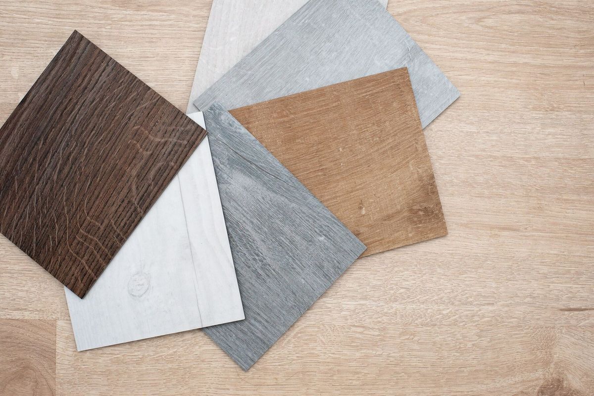 Sample catalog of luxury vinyl floor tiles with a new interior design for a house or floor on a light wooden table.