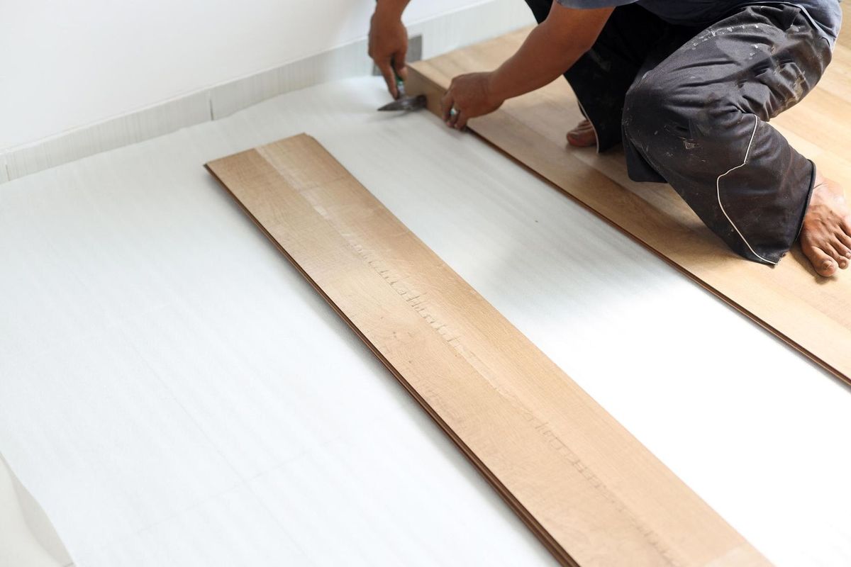 worker joining vinyl floor covering at home renovation