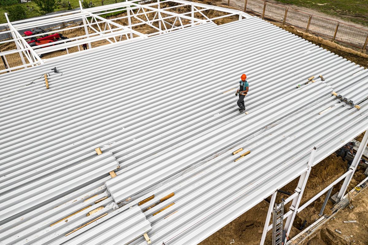 A worker on the roof mounts panels Construction of a frame building Top view