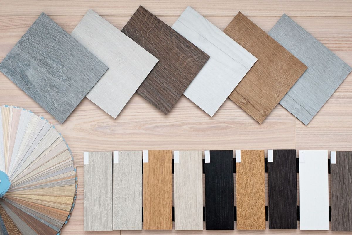 An example of a catalog of luxury vinyl floor tiles and a designer palette with textures with a new interior design for a house or floor on a light wooden table.
